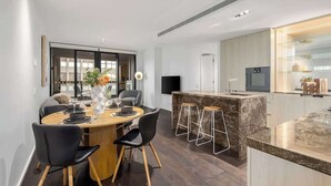 Eine moderne Küche mit Marmorarbeitsplatte, einem eingebauten Backofen und einer Bar mit Hockern.