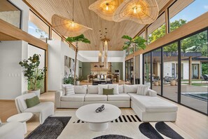 Ein modernes Wohnzimmer mit einer Eckcouch, einem Couchtisch und einem Essbereich, im Hintergrund ist eine Küche zu sehen.