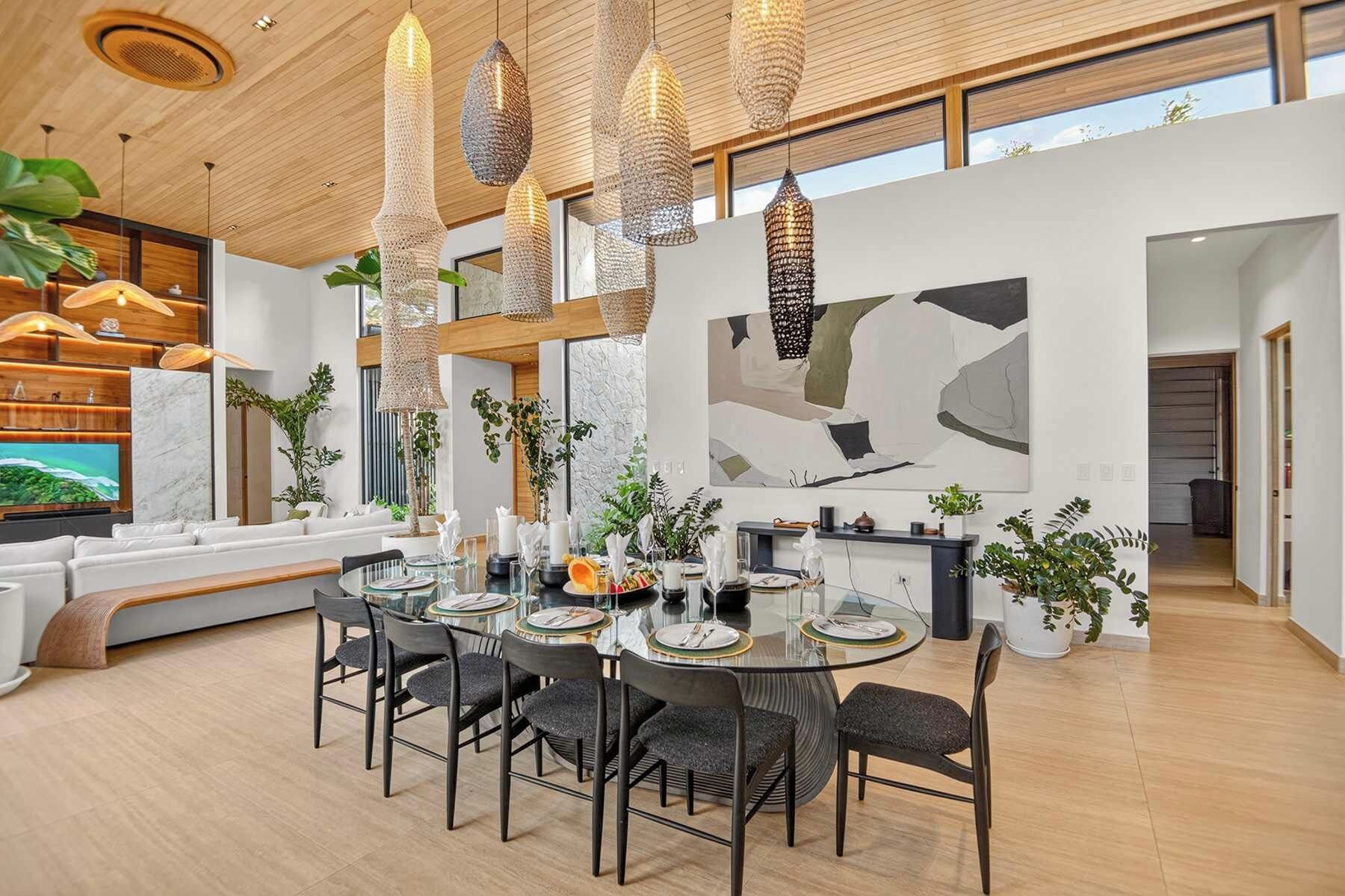 A modern dining area with a round table, black chairs, and a large abstract painting on the wall.