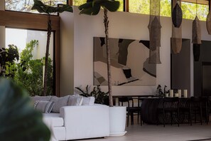 Ein modernes Interieur mit einem weißen Sofa, einem Esstisch, Stühlen und hängenden Leuchten.