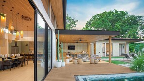 Un espace de vie extérieur moderne comprenant une piscine, un coin repas et un espace salon abrité.