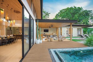 A modern outdoor living area with a pool, dining space, and a covered seating area. - Casa Kaikoo (Hacienda Pinilla)