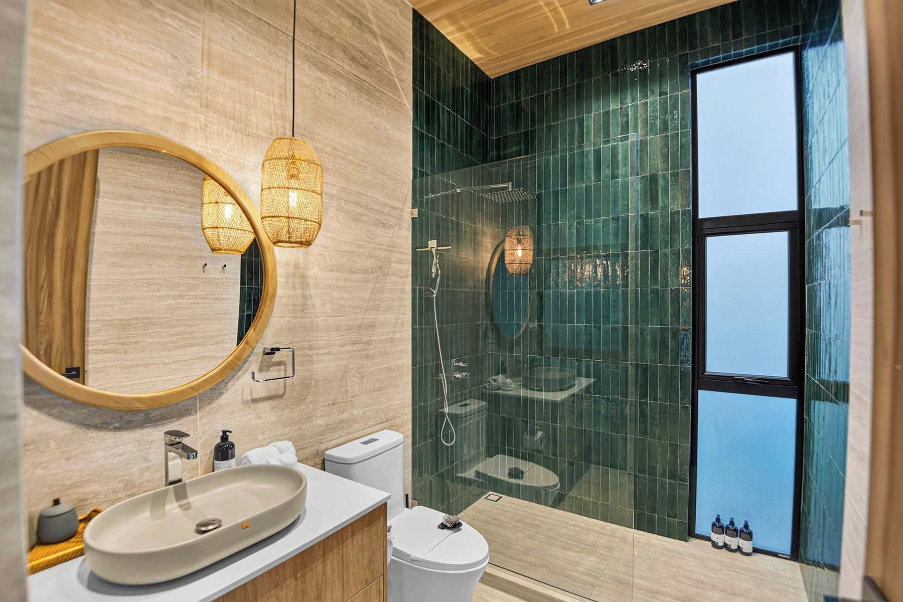 Een moderne badkamer met een grote spiegel, een wastafel, een toilet en een douchecabine met glazen wanden.