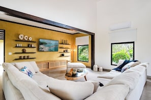 A modern living room with a large sofa, a coffee table, and a painting on the wall.