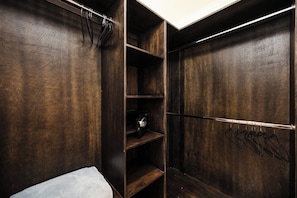 A walk-in closet with wooden shelving, a hanging rod, and a small safe.