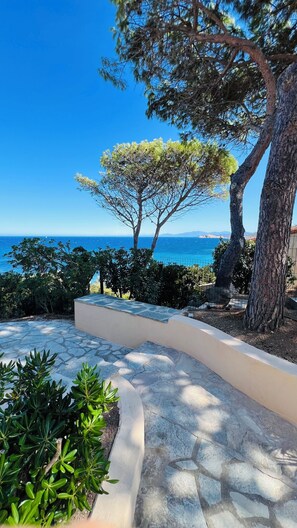 A stone pathway leading to a scenic view of the sea, surrounded by trees and greenery. - Exceptional Marine de Davia villa facing the sea and close to the beaches (Corbara)