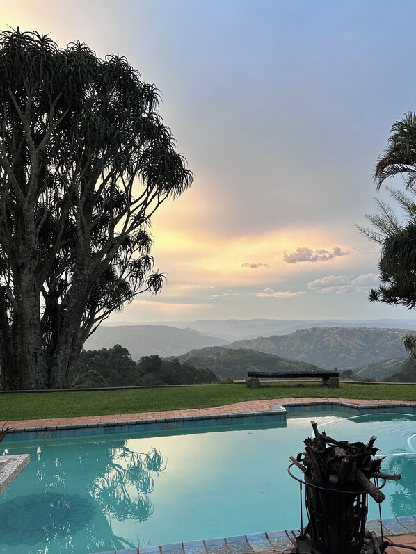 A swimming pool with a view of distant mountains and a large tree.