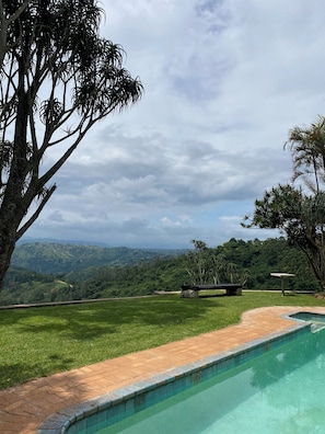 Una piscina con vistas a un paisaje exuberante y colinas lejanas.