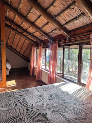 Une pièce avec un plafond en pente, de grandes fenêtres avec des rideaux et un sol à motifs.