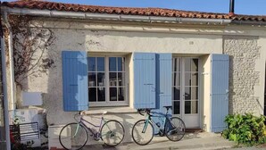 Un edificio con fachada de piedra, contraventanas azules y dos bicicletas estacionadas frente a él.