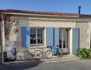Ein Gebäude mit einer Steinfassade, blauen Fensterläden und zwei vor der Tür abgestellten Fahrrädern.