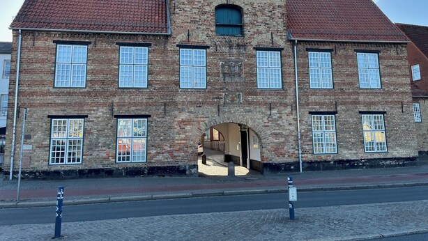 Um edifício histórico com fachada simétrica, várias janelas e uma entrada central.