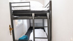 Ein Schlafraum mit Etagenbetten, einem Fenster, einer Tür und einem Handtuch auf dem Boden.
