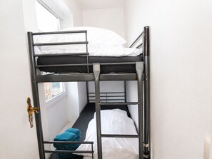 Ein Schlafraum mit Etagenbetten, einem Fenster, einer Tür und einem Handtuch auf dem Boden.