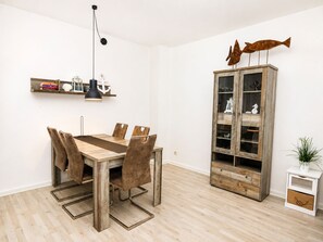 Ein Essbereich mit Holztisch und Stühlen, einer Hängeleuchte und einem Schrank mit Glastüren.