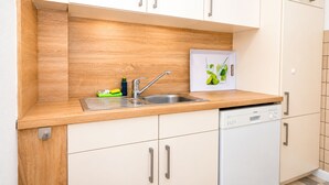 Cozinha moderna com bancada de madeira, pia de aço inoxidável e armários brancos.