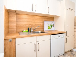 Eine moderne Küche mit Holzarbeitsplatte, Edelstahlspüle und weißen Schränken.
