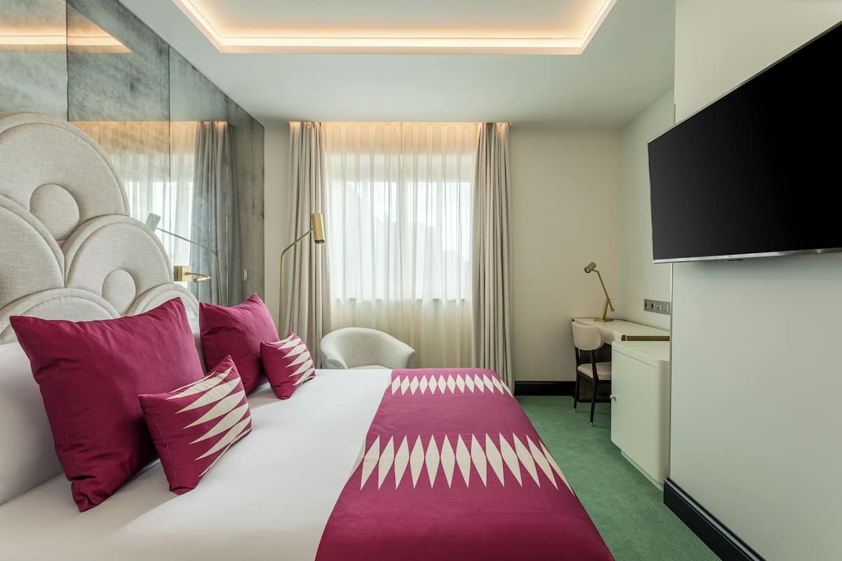 Una habitación de hotel con una cama grande, un escritorio, una silla y un televisor.