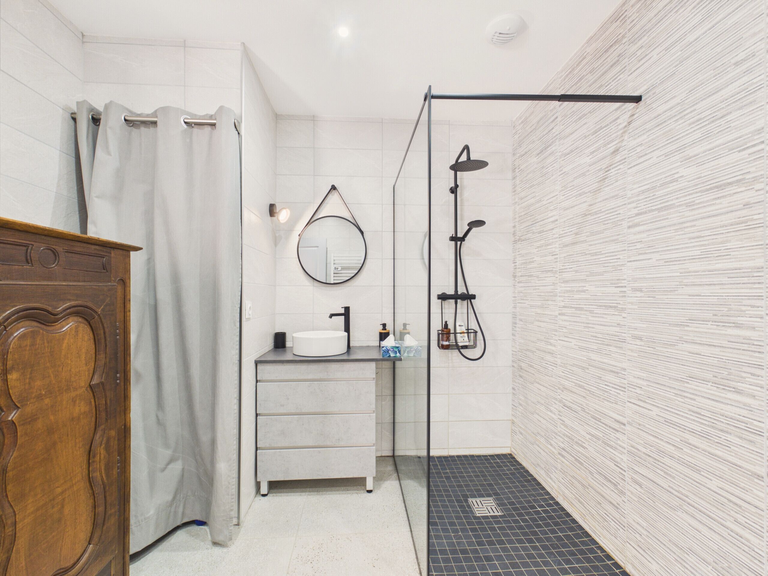 A modern bathroom with a shower, a vanity with a sink, and a mirror.