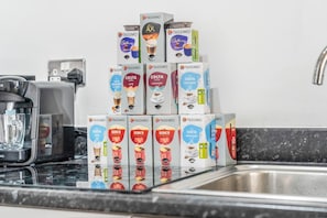 A kitchen counter with a coffee machine and stacks of Tassimo coffee pods. - 1-bed Apartment, Sleeps 6 With Balcony View in West Midlands (Birmingham)