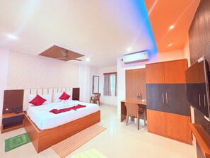A modern hotel room with a large bed, a desk, a wardrobe, and an air conditioning unit. - Puri Hotel Shri Sudama on Seven Hills Rd (Puri)