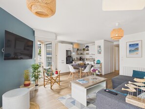 Eine moderne Wohnung mit Wohnzimmer, Essbereich, Küche und einem Balkon.