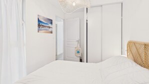 Ein Schlafzimmer mit Bett, einer Tür, einer Wandleuchte und einem Bild.