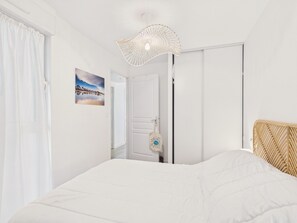 Ein Schlafzimmer mit Bett, einer Tür, einer Wandleuchte und einem Bild.