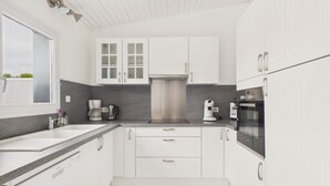 Una cucina moderna con mobili bianchi, una cappa aspirante in acciaio inossidabile e un forno integrato.