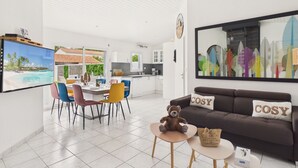 Un soggiorno moderno con divano, televisione e zona pranzo con sedie e tavolo.