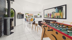 Un soggiorno moderno con un tavolo da calcio, una TV e una zona pranzo con sedie e tavolo.