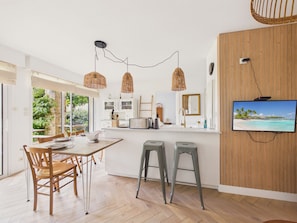 Eine moderne Küche mit einer großen Kochinsel, Holzböden und einem an der Wand montierten Fernseher.