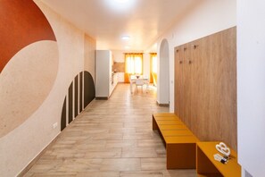 A hallway with a wooden bench, a reception desk, and a dining area in the background. - Dream House - Phoenix (Marina di Palma)