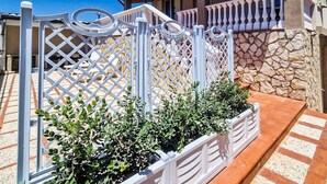 A white metal fence with a lattice design, a stone wall, and a tiled floor. - Dream House - Phoenix (Marina di Palma)