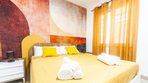 A hotel room with a bed, pillows, a nightstand, and a wall with abstract art. - Dream House - Phoenix (Marina di Palma)