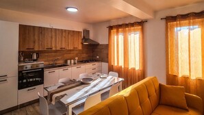 A compact kitchen with modern appliances, a dining table, and a yellow sofa. - Dream House - Phoenix (Marina di Palma)