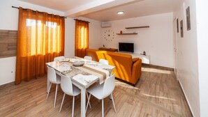 A modern living room with a dining table, white chairs, a sofa, a TV, and a fireplace. - Dream House - Phoenix (Marina di Palma)