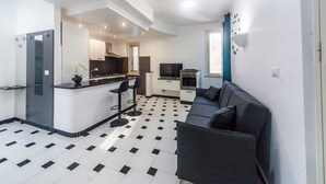 Ett kompakt bostadsutrymme med ett litet kök, en soffa och en matplats.