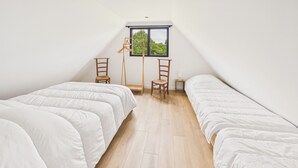 Una habitación con dos camas, un ventanal y suelo de madera.
