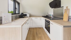 Una cocina moderna con armarios blancos, microondas, estufa y un ventanal.