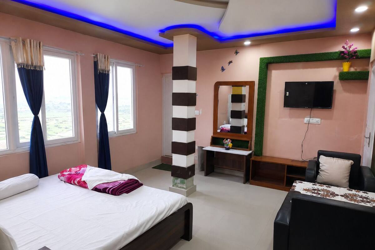 A hotel room with a bed, a desk, a chair, a TV, and a window with curtains.