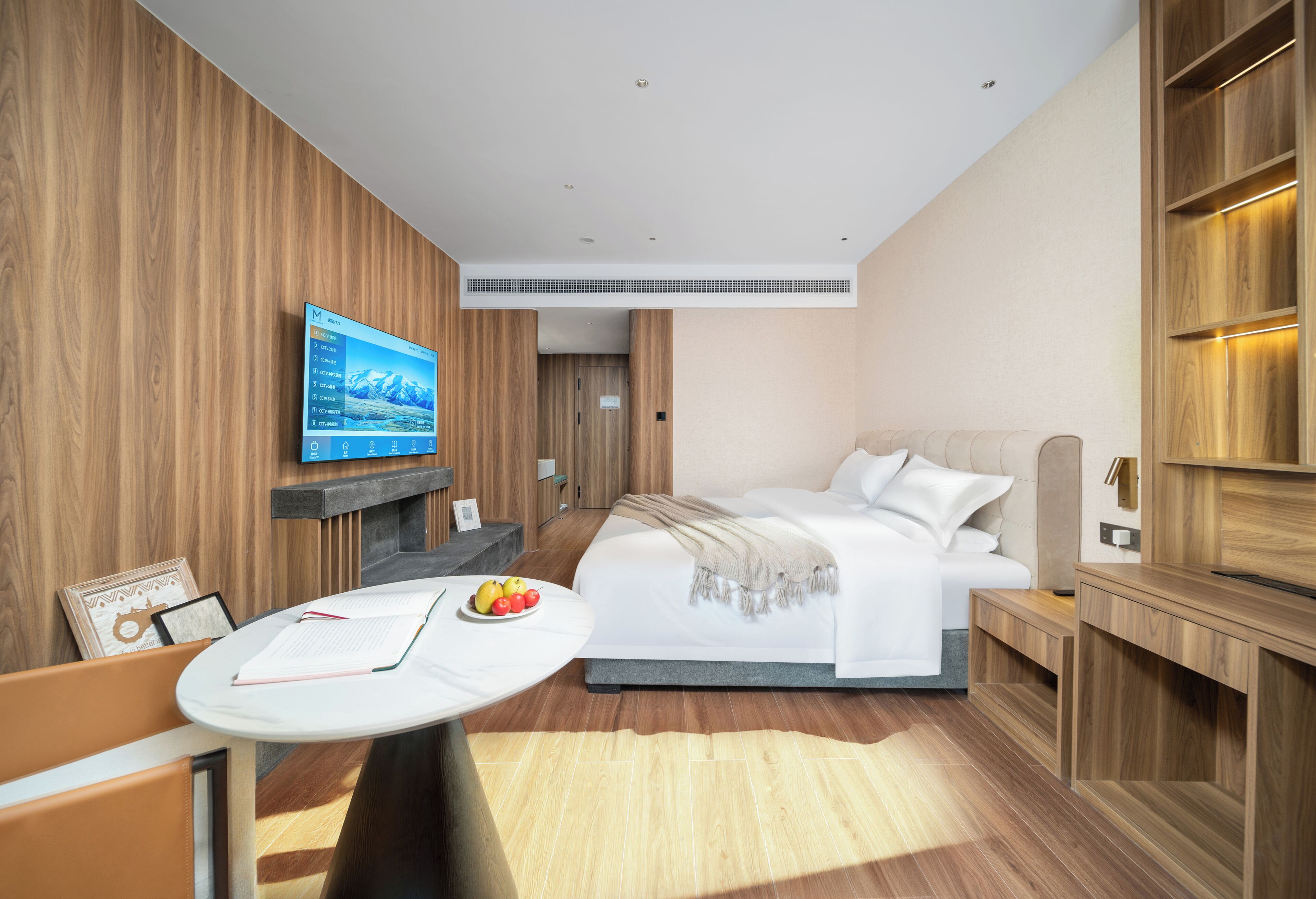 Una habitación de hotel moderna con cama, mesita de noche, televisor y vistas a las montañas.