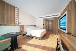 Una habitación de hotel moderna con una cama, televisión, escritorio y zona de estar.