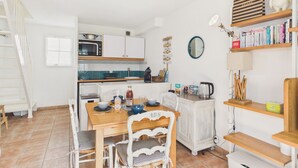 Una cocina con armarios blancos, microondas, cafetera y una mesa de comedor con sillas.