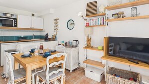 Cocina compacta con microondas, estufa y comedor con sillas y mesa.