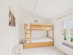 Ein Stockbett in einem Zimmer mit weißen Wänden, einem kleinen Tisch und einem Fenster mit Blick.