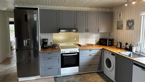 Una cocina moderna con gabinetes grises, un refrigerador de acero inoxidable, una estufa, un microondas y una lavadora.