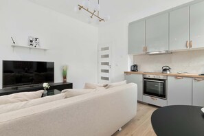 Ein modernes Wohnzimmer mit Flachbildfernseher, einem beigefarbenen Sofa und einem schwarzen Couchtisch.