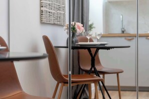Ett modernt matområde med en glasvägg, läderstolar, ett bord med en vas med blommor och utsikt över köket.