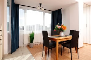 Ein moderner Essbereich mit einem Holztisch, schwarzen Stühlen, einer Topfpflanze und einem Blumenstrauß.